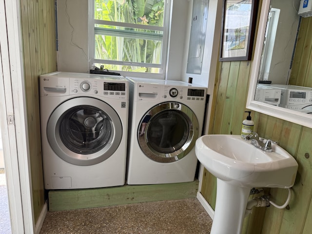 laundry area with washing machine and dryer, wood walls, and laundry area