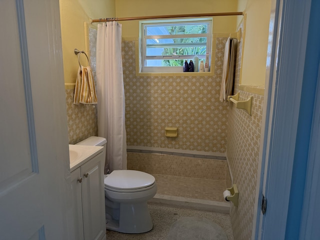 bathroom featuring vanity, toilet, wainscoting, and tiled shower
