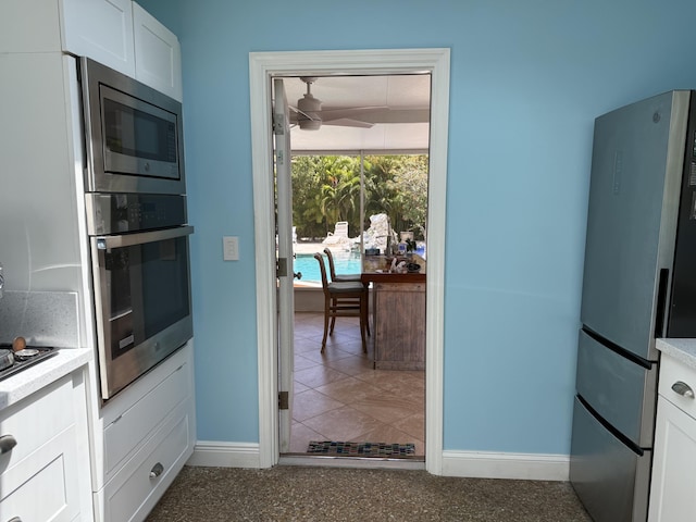 kitchen with appliances with stainless steel finishes, baseboards, ceiling fan, and white cabinetry