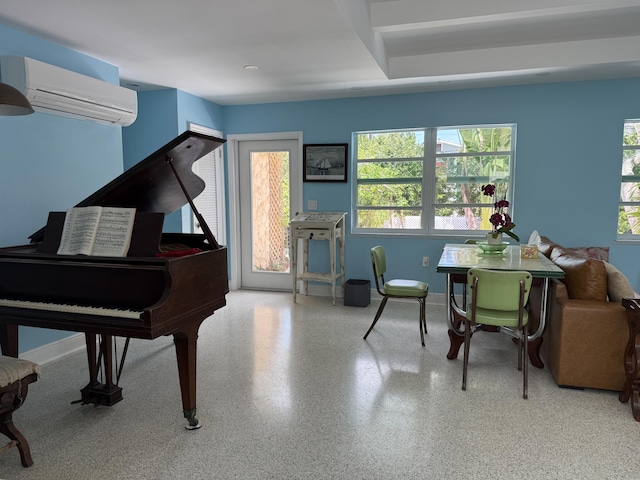 sitting room featuring baseboards, a wealth of natural light, and an AC wall unit