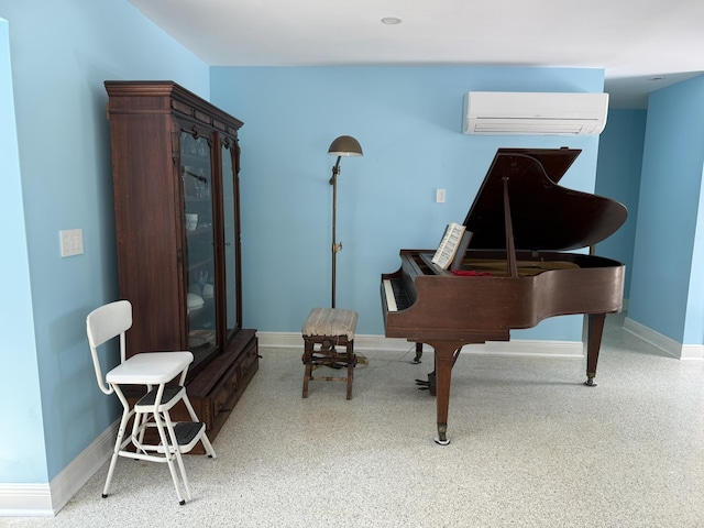 living area featuring baseboards and an AC wall unit