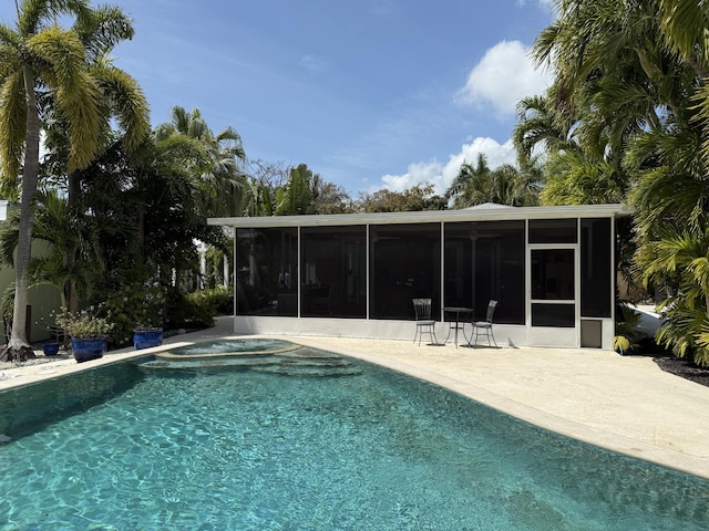 pool with a hot tub, a sunroom, and a patio