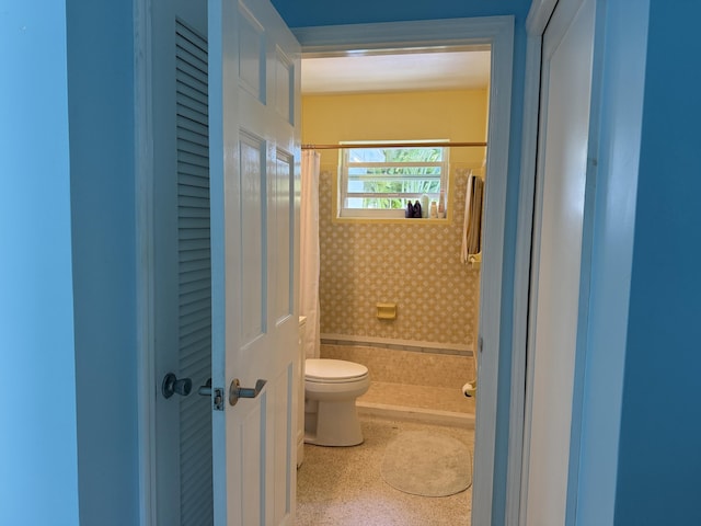 full bath with toilet and a shower with curtain