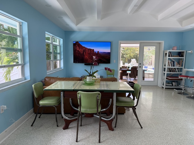 dining space with speckled floor, beam ceiling, and french doors