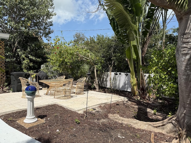 view of yard with a patio, fence, and outdoor dining space
