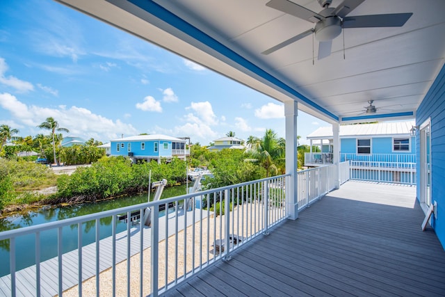 wooden deck with a water view and a ceiling fan