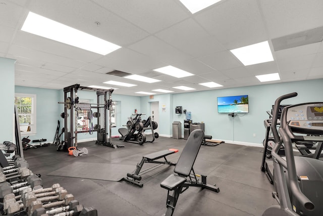 exercise room with a drop ceiling and baseboards