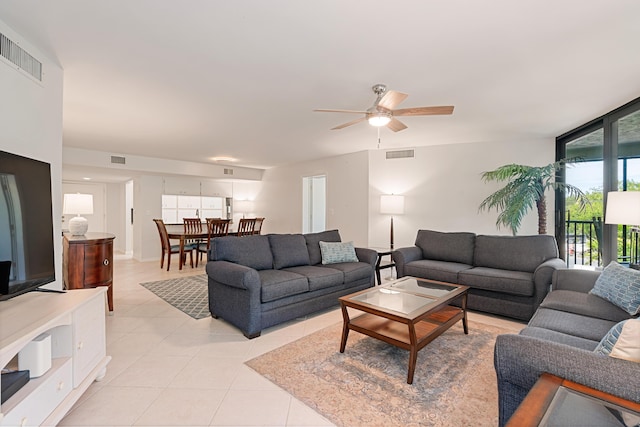 living room featuring a ceiling fan, light tile patterned floors, a wall of windows, and visible vents