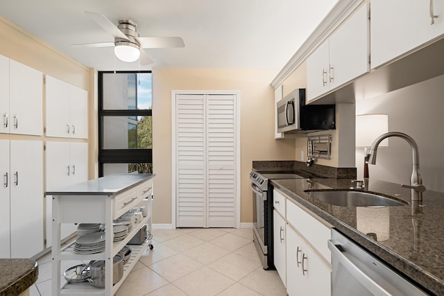 kitchen with light tile patterned floors, stainless steel appliances, a sink, ceiling fan, and white cabinets