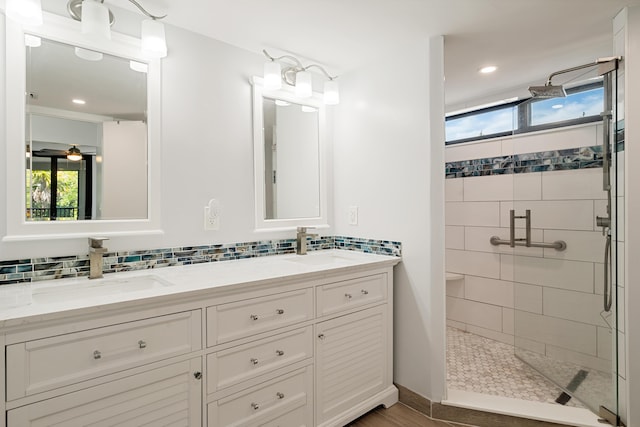 bathroom with decorative backsplash, a sink, a stall shower, and plenty of natural light