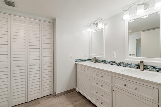 full bath with decorative backsplash, visible vents, a sink, and wood finished floors