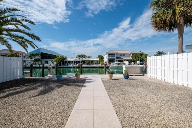 exterior space with a water view, a dock, and fence