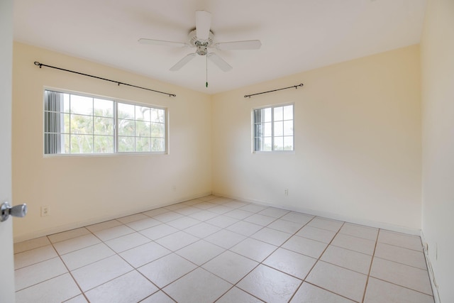 spare room featuring light tile patterned floors, baseboards, and ceiling fan
