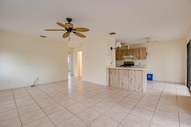 kitchen featuring light tile patterned flooring, light countertops, a ceiling fan, stainless steel range, and under cabinet range hood
