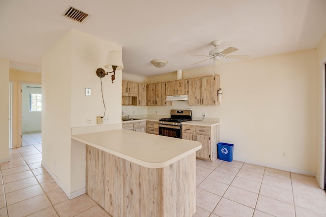 kitchen featuring light countertops, visible vents, under cabinet range hood, gas range, and light tile patterned floors