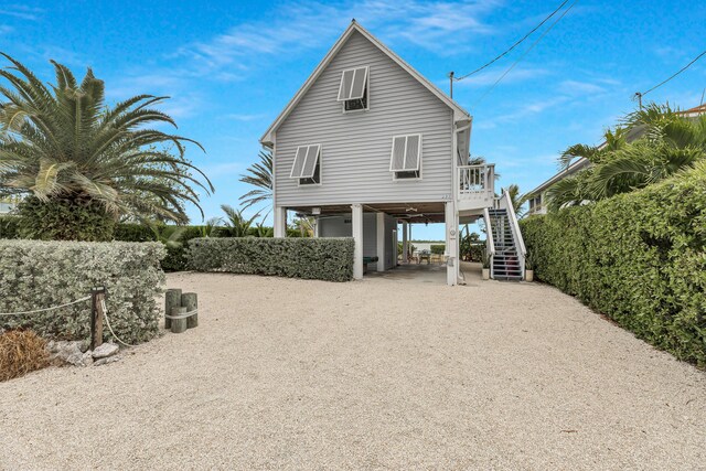 rear view of house featuring driveway, stairway, and a carport