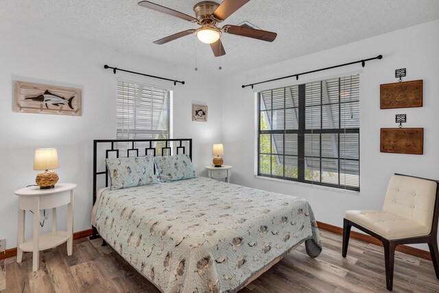 bedroom with ceiling fan, a textured ceiling, baseboards, and wood finished floors