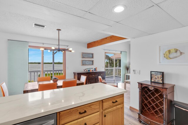 kitchen with light wood finished floors, plenty of natural light, visible vents, and a chandelier