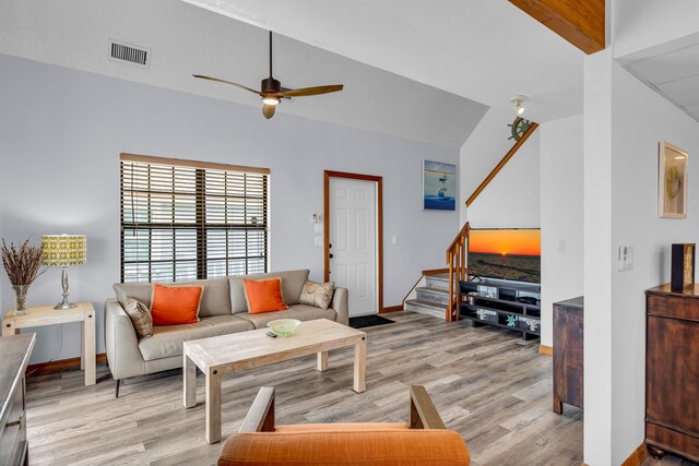 living room featuring light wood-style floors, visible vents, stairway, and a ceiling fan