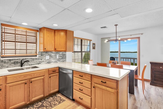 kitchen featuring a peninsula, a sink, visible vents, light countertops, and dishwasher