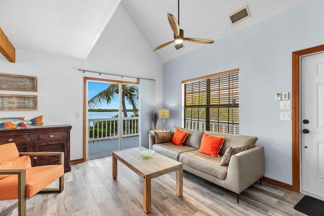 living area featuring visible vents, light wood-style flooring, ceiling fan, a textured ceiling, and baseboards