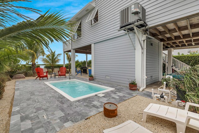 view of swimming pool with stairs, a patio area, and cooling unit