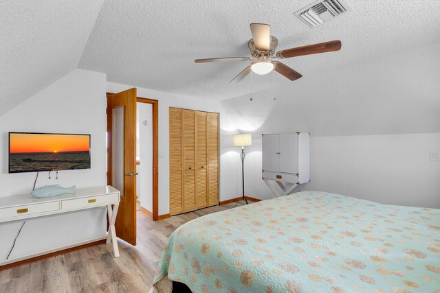 bedroom with lofted ceiling, visible vents, a ceiling fan, a textured ceiling, and wood finished floors