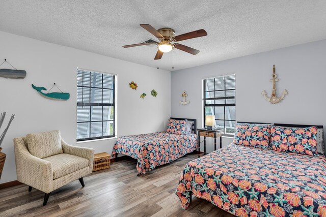 bedroom featuring multiple windows, ceiling fan, a textured ceiling, and wood finished floors