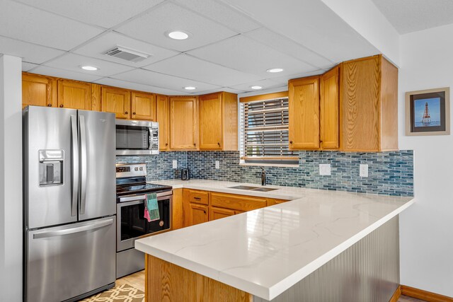 kitchen featuring a peninsula, a sink, visible vents, appliances with stainless steel finishes, and light stone countertops