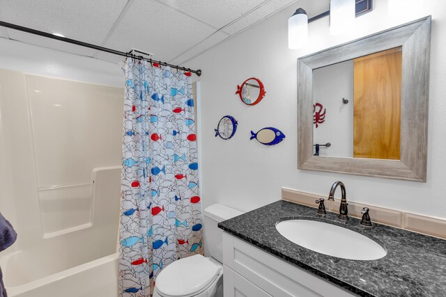 bathroom with a paneled ceiling, shower / bath combo, vanity, and toilet