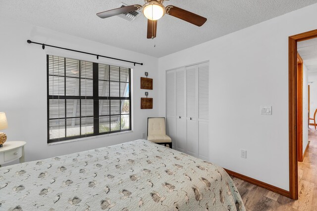 bedroom featuring baseboards, ceiling fan, wood finished floors, a textured ceiling, and a closet