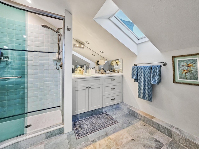 bathroom featuring lofted ceiling with skylight, a shower stall, and vanity