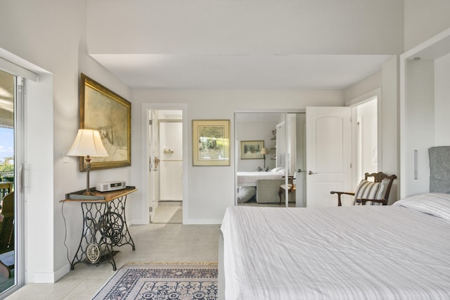 bedroom featuring light tile patterned floors, ensuite bathroom, and baseboards