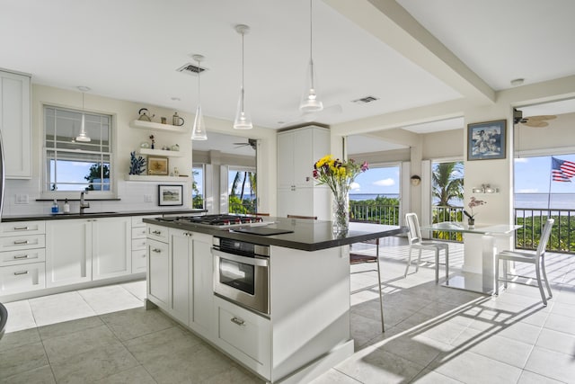 kitchen featuring stainless steel appliances, dark countertops, white cabinets, and a kitchen island