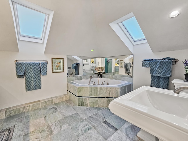 bathroom with a sink, vaulted ceiling with skylight, and a bath