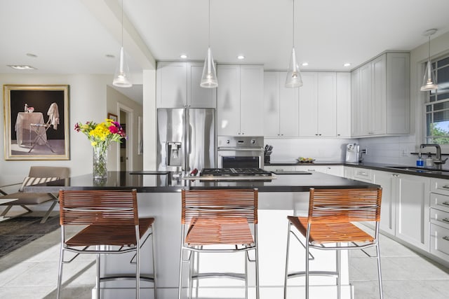 kitchen with appliances with stainless steel finishes, dark countertops, a kitchen island, and a kitchen breakfast bar