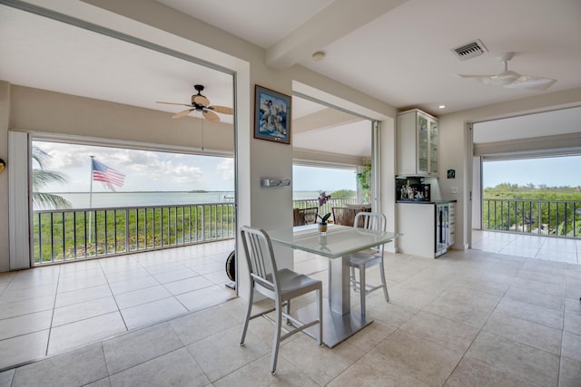 dining area featuring a water view, plenty of natural light, ceiling fan, and visible vents