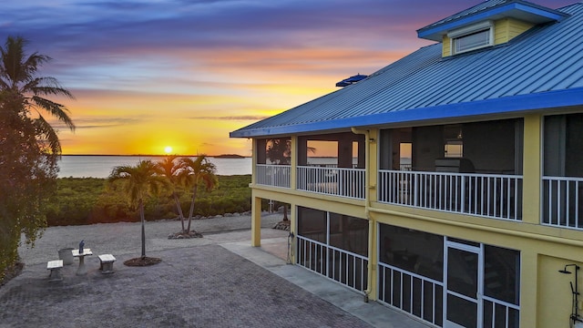 exterior space featuring metal roof, a patio, a standing seam roof, and a water view