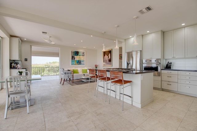 kitchen with appliances with stainless steel finishes, dark countertops, decorative light fixtures, and visible vents