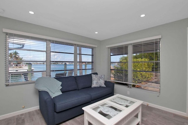 living area featuring baseboards, recessed lighting, a water view, and wood finished floors