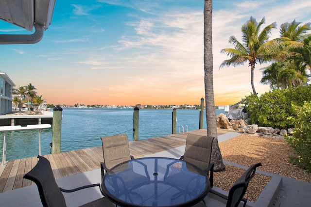 view of dock featuring outdoor dining area and a water view