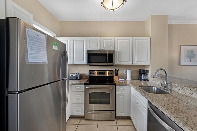 6005 Marina Villa Dr Unit C-019, Duck, FL 33050 - kitchen featuring appliances with stainless steel finishes, a sink, white cabinets, light tile patterned floors, and light stone countertops