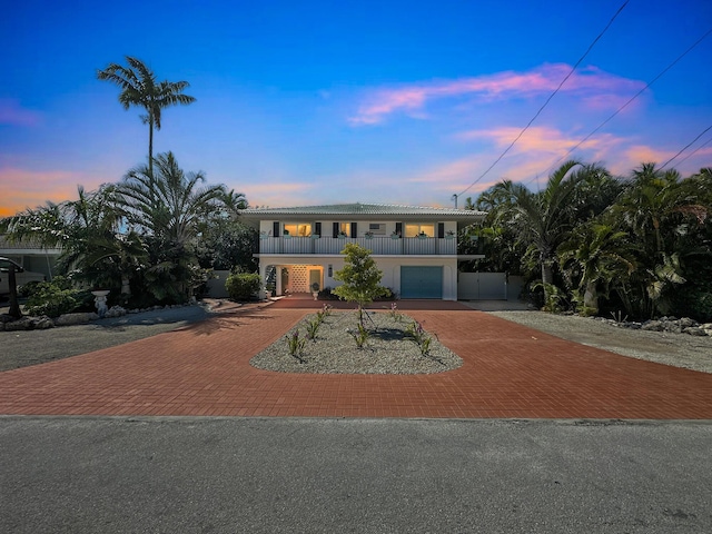 661 12th St, Key Colony, FL 33051 - view of front of house with decorative driveway, a balcony, a tiled roof, an attached garage, and stucco siding