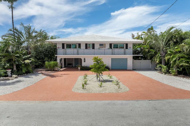 661 12th St, Key Colony, FL 33051 - coastal inspired home featuring decorative driveway, a balcony, a tile roof, stucco siding, and a garage