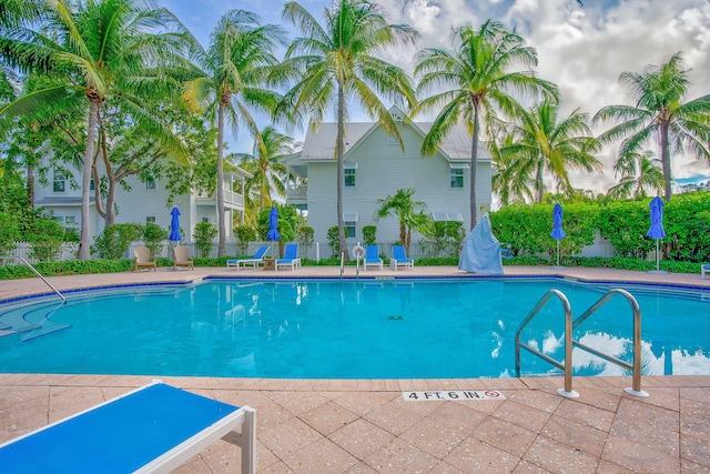 community pool with a patio area and fence