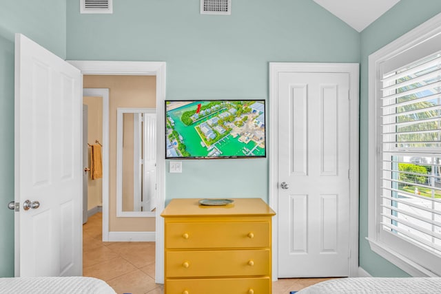 bedroom featuring light tile patterned floors, visible vents, baseboards, and vaulted ceiling