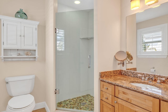 bathroom with a stall shower, toilet, vanity, and baseboards