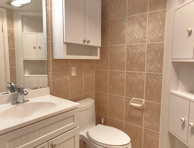 half bathroom featuring toilet, tile walls, and vanity