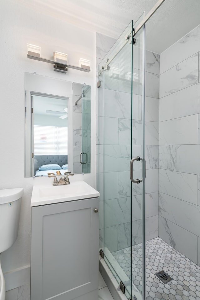 ensuite bathroom with vanity, marble finish floor, toilet, connected bathroom, and a shower stall