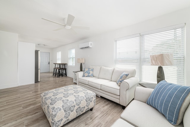 living room with light wood-style floors, a ceiling fan, and an AC wall unit